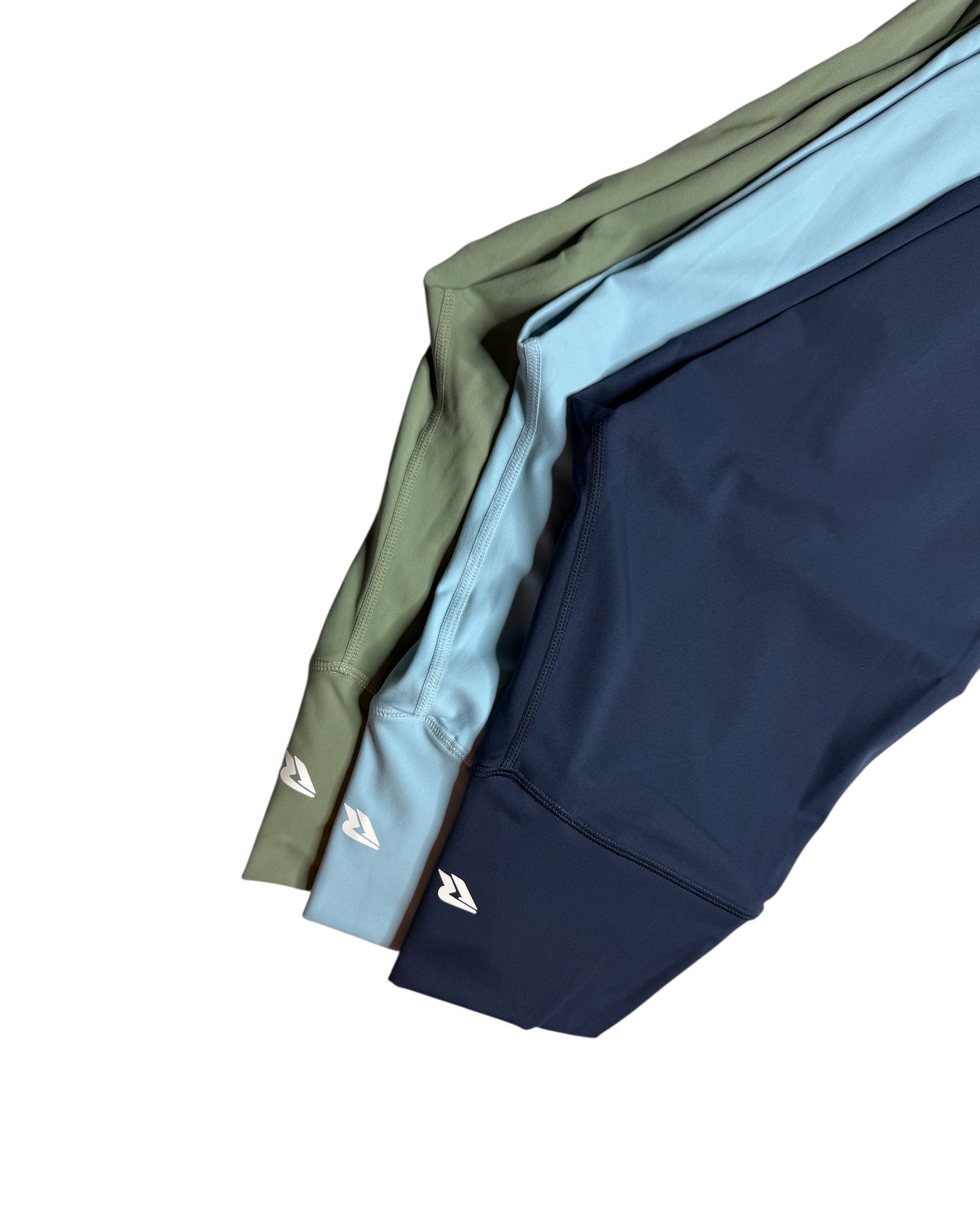 Three pairs of pants in green, blue, and navy on a white background